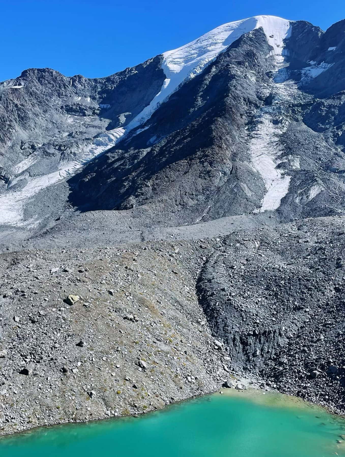 Lac glaciaire turquoise au pied d'un sommet enneigé, près de Verbier